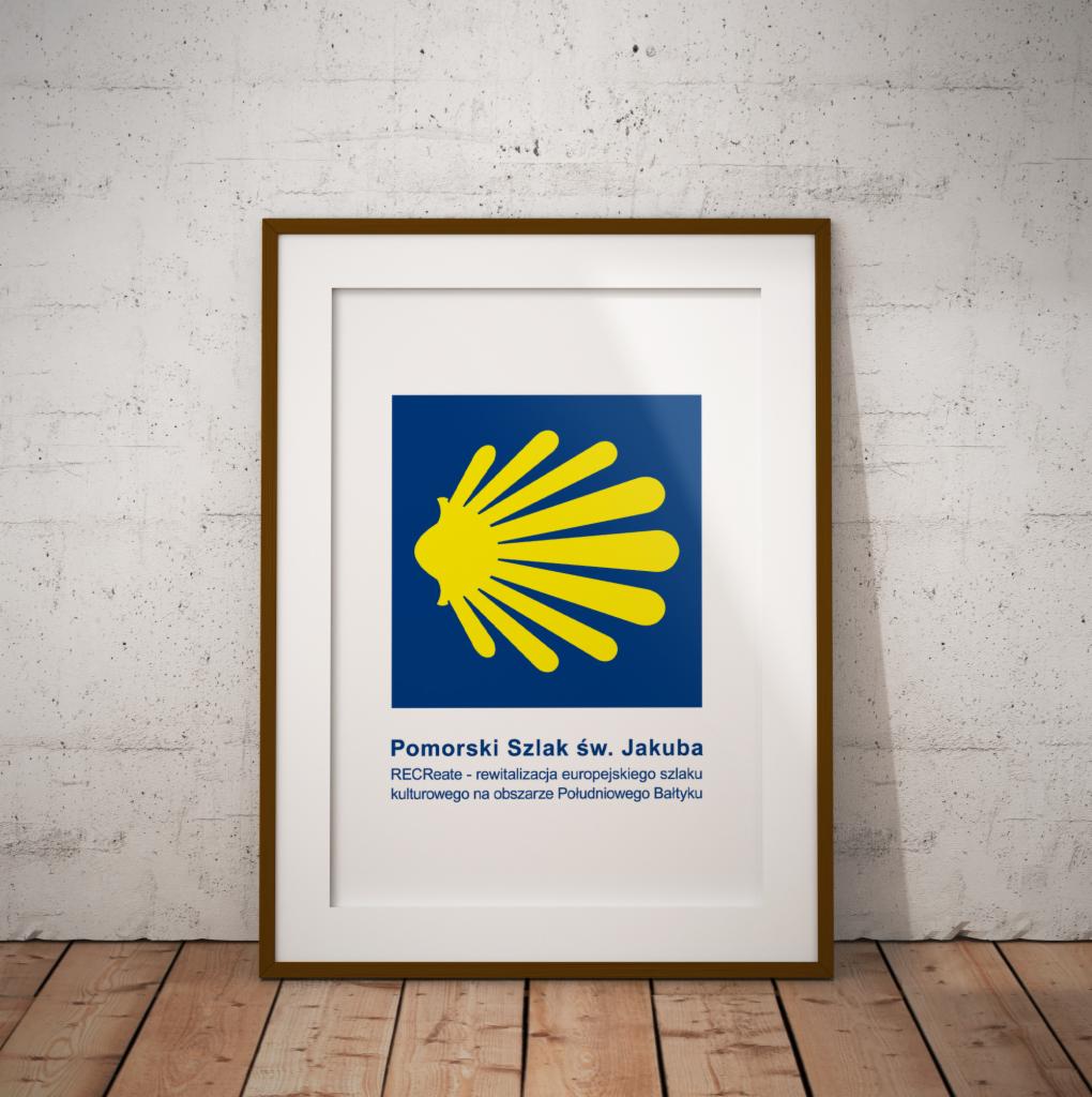Oprawiony plakat z symbolem żółtej muszli na niebieskim tle, promujący Pomorski Szlak św. Jakuba, stojący na drewnianej podłodze przy białej, teksturowanej ścianie.