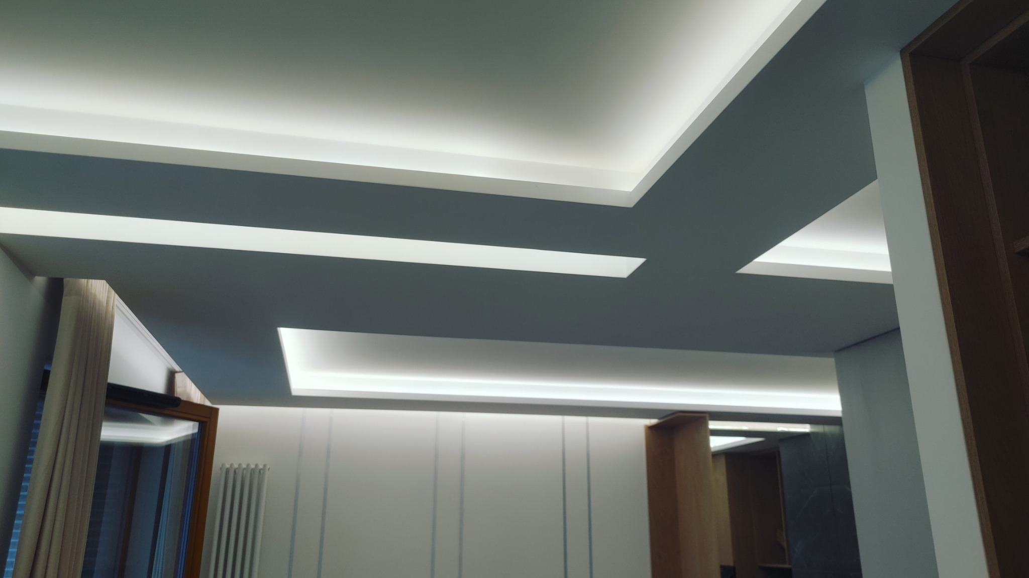 Nowoczesny sufit podwieszany z oświetleniem LED w minimalistycznym wnętrzu, widok z dołu.