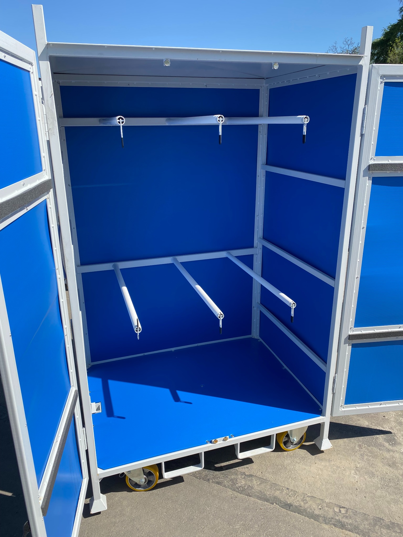 Otwarta metalowa szafa na kółkach z niebieskim wypełnieniem, widoczne uchwyty na narzędzia.