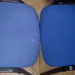 Dwa krzesła biurowe z niebieską tapicerką, jedno z widocznymi plamami przed czyszczeniem, drugie po czyszczeniu, ukazujące różnicę w wyglądzie.