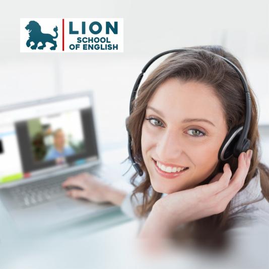 Uśmiechnięta kobieta z zestawem słuchawkowym prowadzi lekcję online, widoczna na ekranie laptopa.