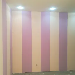 Ściana w pokoju po malowaniu w szerokie, pionowe pasy w kolorach liliowym i kremowym, widoczne gniazdko elektryczne przy podłodze.