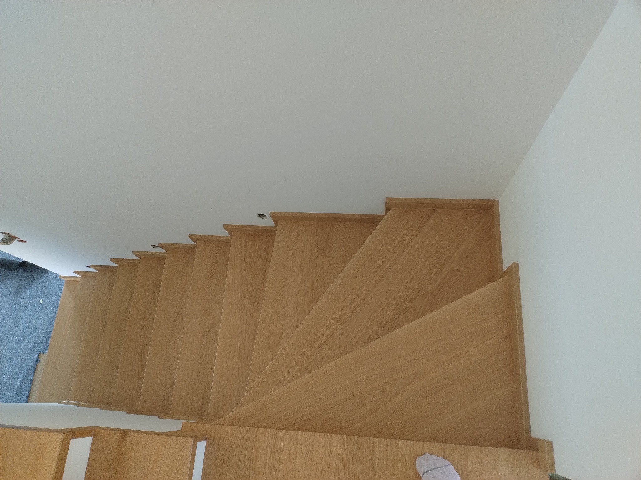 Drewniane schody z jasnego drewna, widok z góry, ukazujące precyzyjne wykonanie i estetyczne wykończenie w nowoczesnym wnętrzu.