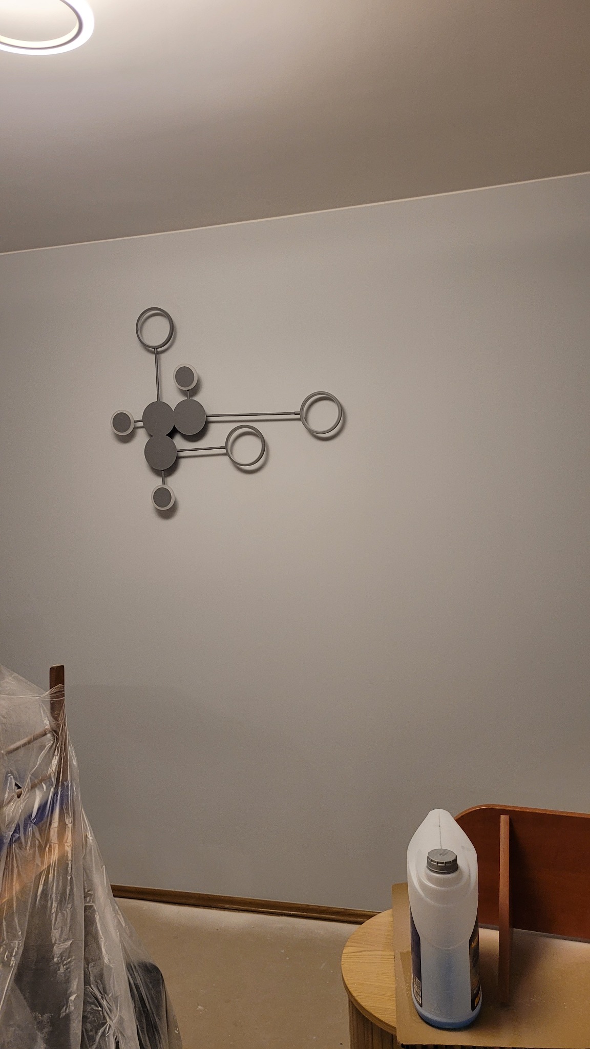 Ściana po malowaniu w Markach z dekoracją ścienną. Widoczny pojemnik z farbą i zabezpieczone meble folią malarską. Świeżo odmalowane wnętrze.