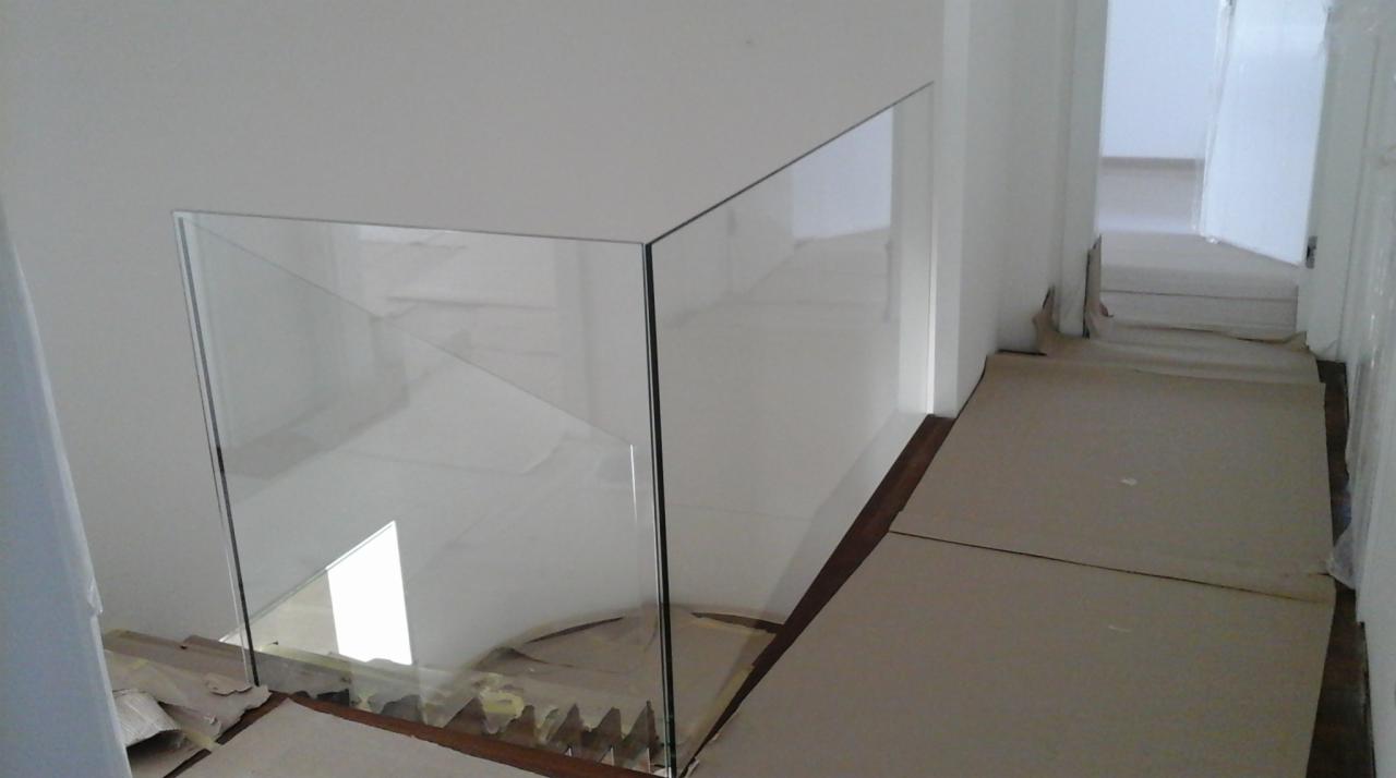 Szklana barierka zabezpieczająca schody, widoczne zabezpieczenia podłogi kartonem podczas montażu.