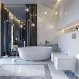 Justyna Tatys Luxury Interiors - Elegancka łazienka z wolnostojącą wanną i marmurowymi płytami, oświetlona nowoczesnym, rozgałęzionym żyrandolem, z widokiem na sypialnię przez szklaną ścianę.