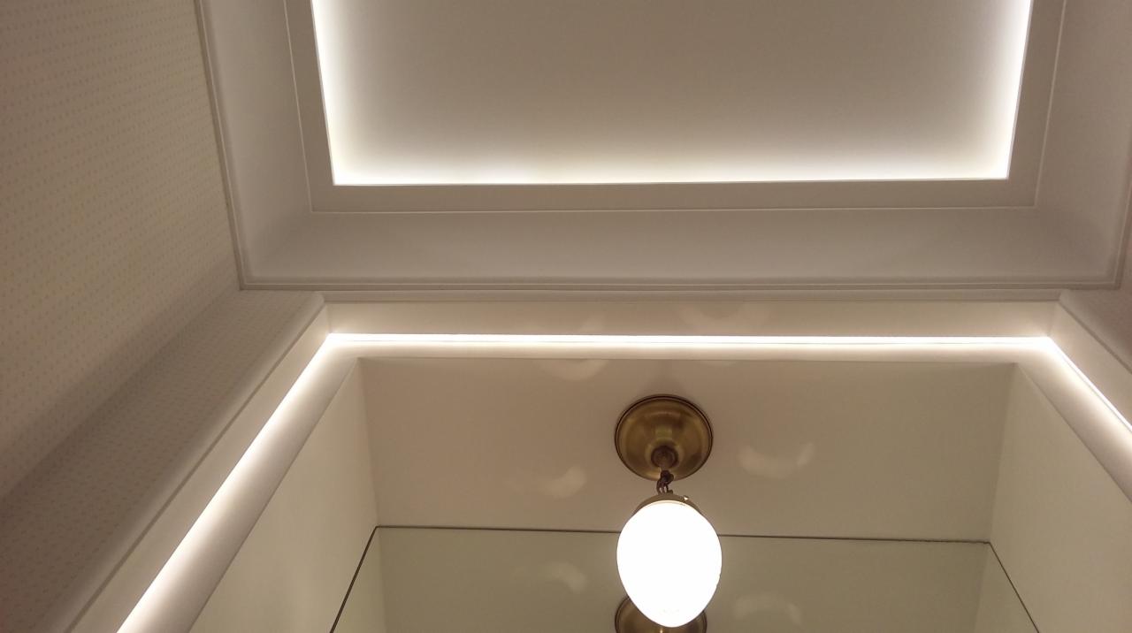 Oświetlenie LED w nowoczesnej łazience w Poznaniu, podkreślające krawędzie sufitu i ścian, z okrągłą lampą wiszącą z metalowym mocowaniem.