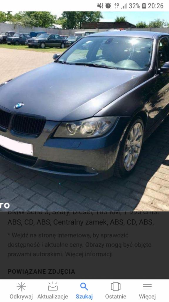 Szary samochód BMW serii 3 zaparkowany na brukowanej powierzchni, widoczne inne auta w tle.