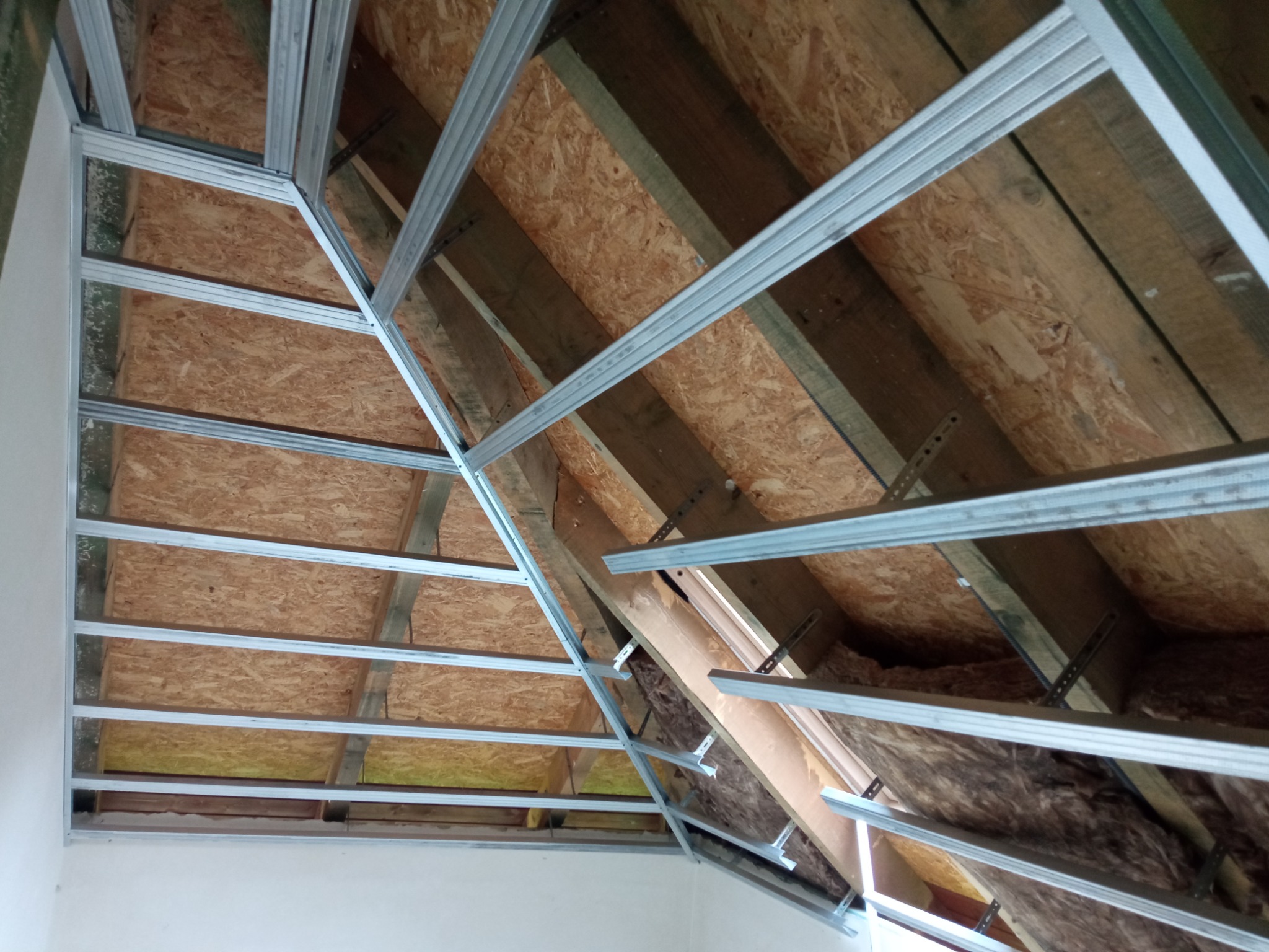 Szkielet metalowy pod płytę karton gips na poddaszu, widoczne ocieplenie wełną mineralną, konstrukcja drewniana dachu.