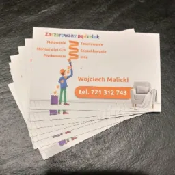Stos wizytówek firmy remontowej z ilustracją malarza z pędzlem i listą usług: malowanie, tapetowanie, montaż płyt G-K, szpachlowanie, płytkowanie i inne, oraz danymi kontaktowymi Wojciech Malicki...