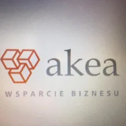 Logo firmy AKEA: trzy połączone pomarańczowe sześciany, nazwa firmy w szarym kolorze i napis 'WSPARCIE BIZNESU' poniżej.