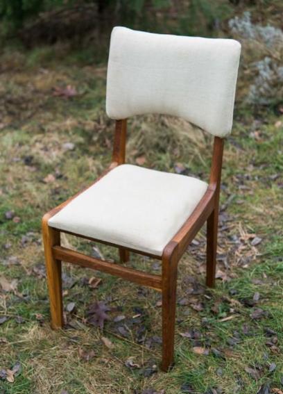 Odrestaurowane krzesło z drewnianą ramą i jasną, tapicerowaną powierzchnią siedziska i oparcia, ustawione na trawie w plenerze.