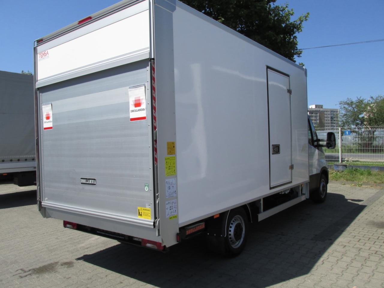 Biały samochód dostawczy typu furgon z windą załadowczą Dhollandia, zaparkowany na kostce brukowej w słoneczny dzień.