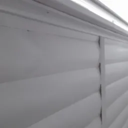 Fragment pomalowanej na biało boazerii z listwą ozdobną, widok z bliska na świeżą farbę i strukturę drewna.