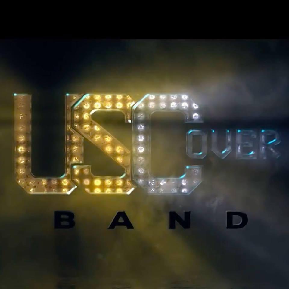 Podświetlane logo zespołu 'USC Cover Band' z efektem dymu, litery 'USC' z żółtymi żarówkami, 'OVER' z białymi, a 'BAND' w kolorze czarnym.