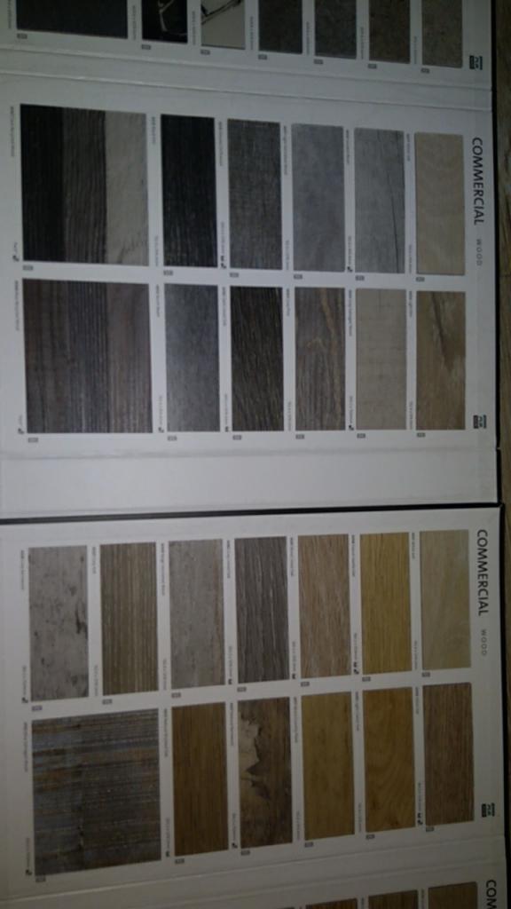 Katalog z próbkami paneli podłogowych różnych kolorów i wzorów, z napisem 'COMMERCIAL WOOD' na boku.