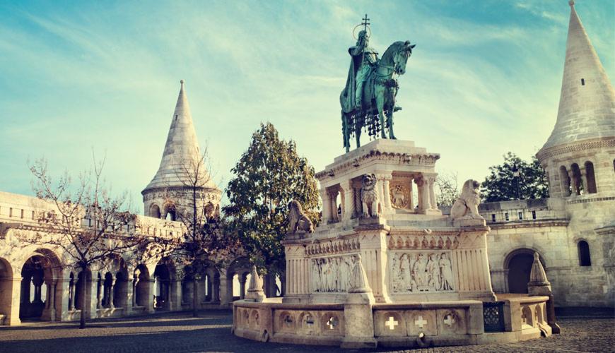 Pomnik świętego króla na koniu, otoczony kamiennymi budowlami z wieżami, prawdopodobnie zorganizowany wyjazd z Oświęcimia.