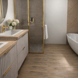 Przedsiębiorstwo Budowlane Limax Sp. z o.o. - Nowoczesna łazienka z drewnopodobną podłogą i ścianami, białą wanną wolnostojącą i szafką z umywalkami. Kabina prysznicowa ze złotymi ramami.