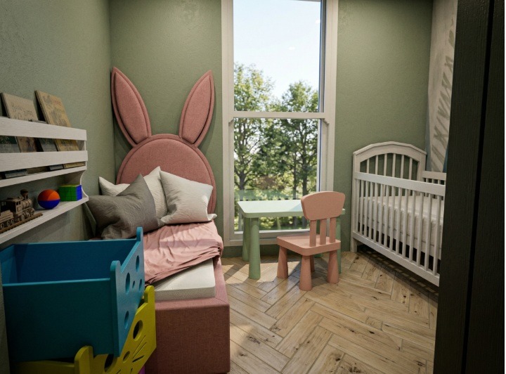 Umeblowany pokój dziecięcy z łóżkiem z zagłówkiem w kształcie uszu królika, stolikiem i krzesełkiem oraz białym łóżeczkiem. Jasne, naturalne światło.