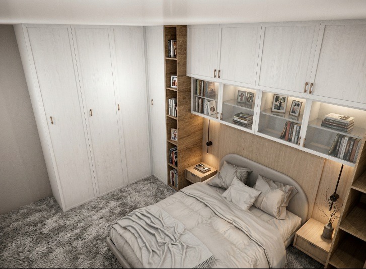 Jasna sypialnia z zabudową meblową: szafy, regał i szafki nad łóżkiem. Drewniane wykończenie, szary dywan i pościel. Oświetlenie punktowe.
