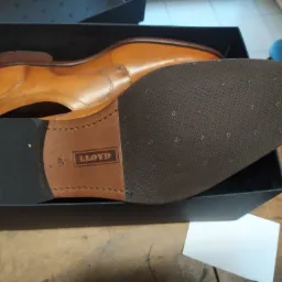 Brązowe, skórzane męskie półbuty marki Lloyd w czarnym pudełku, widoczna podeszwa z logo i czerwonym akcentem na pięcie.