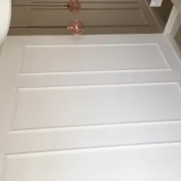 Biała ściana z dekoracyjnymi listwami i dwoma szklanymi lampami w odcieniach różu, widok z dołu, minimalistyczny design.