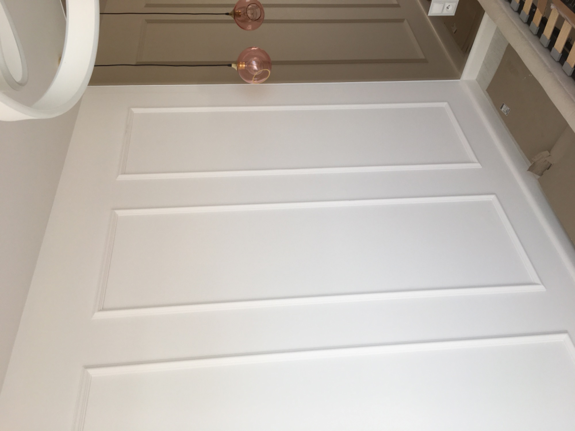 Biała ściana z dekoracyjnymi listwami i dwoma szklanymi lampami w odcieniach różu, widok z dołu, minimalistyczny design.