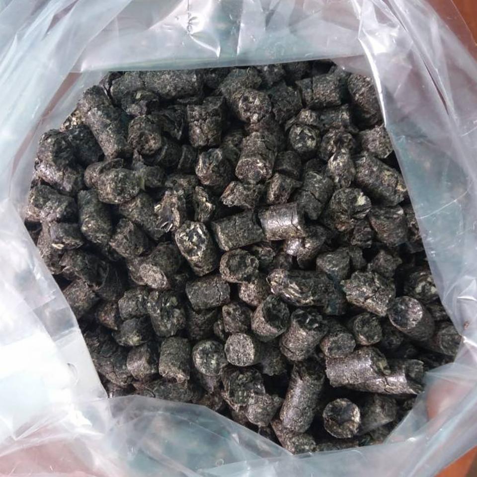 Worek wypełniony ciemnym agropelletem o nieregularnej powierzchni, widoczne ślady pyłu i drobne pęknięcia.