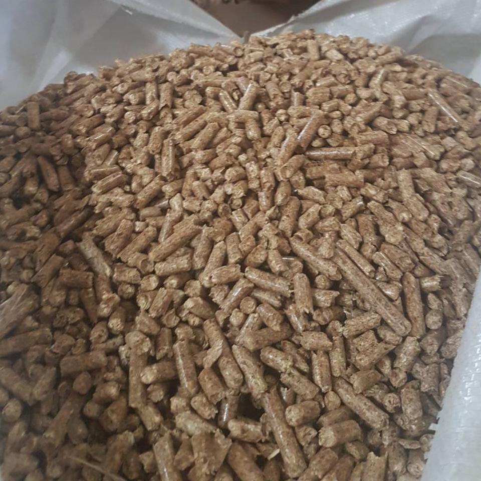 Wypełniony po brzegi worek z jasnobrązowym pelletem drzewnym, widoczne pojedyncze granulki.