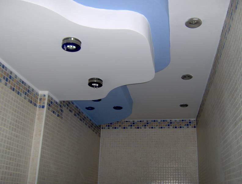 Sufit podwieszany w łazience z oświetleniem punktowym i niebieskim akcentem, wykończony mozaiką.