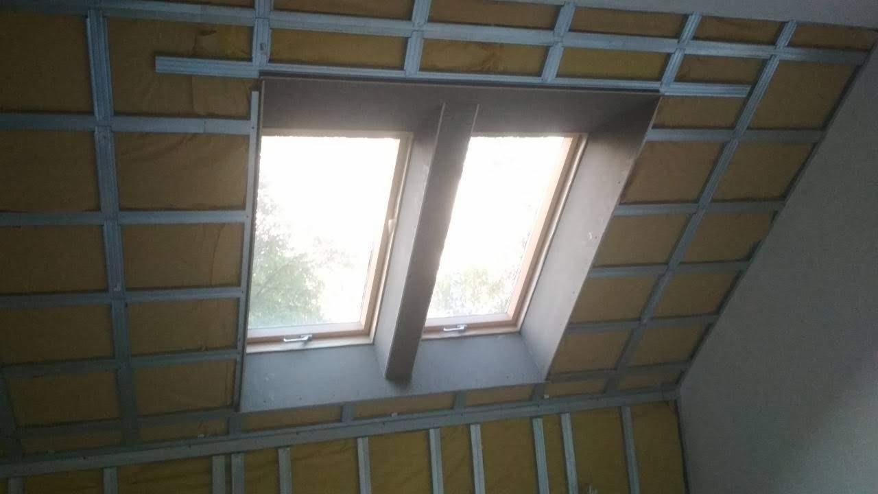 Stelaż metalowy pod płyty gipsowo-kartonowe na poddaszu, widoczne okna dachowe i ocieplenie wełną mineralną, etap prac wykończeniowych.