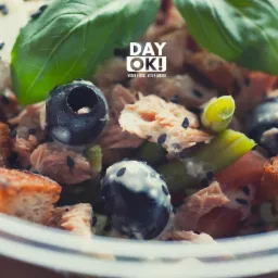 Kompozycja sałatki z tuńczykiem, oliwkami, grzankami i bazylią, posypana czarnym sezamem, z logo 'DAY OK!'