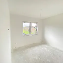 Wnętrze pokoju po świeżym pomalowaniu na biało w Myśliborzu, widoczne ślady po szpachlowaniu na podłodze i wystający kabel z sufitu.