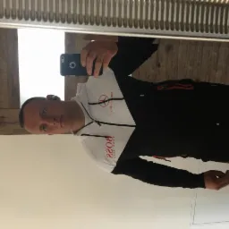 Mężczyzna robi selfie w lustrze, ubrany w dres marki Hugo Boss, widoczne elementy wykończenia wnętrza.