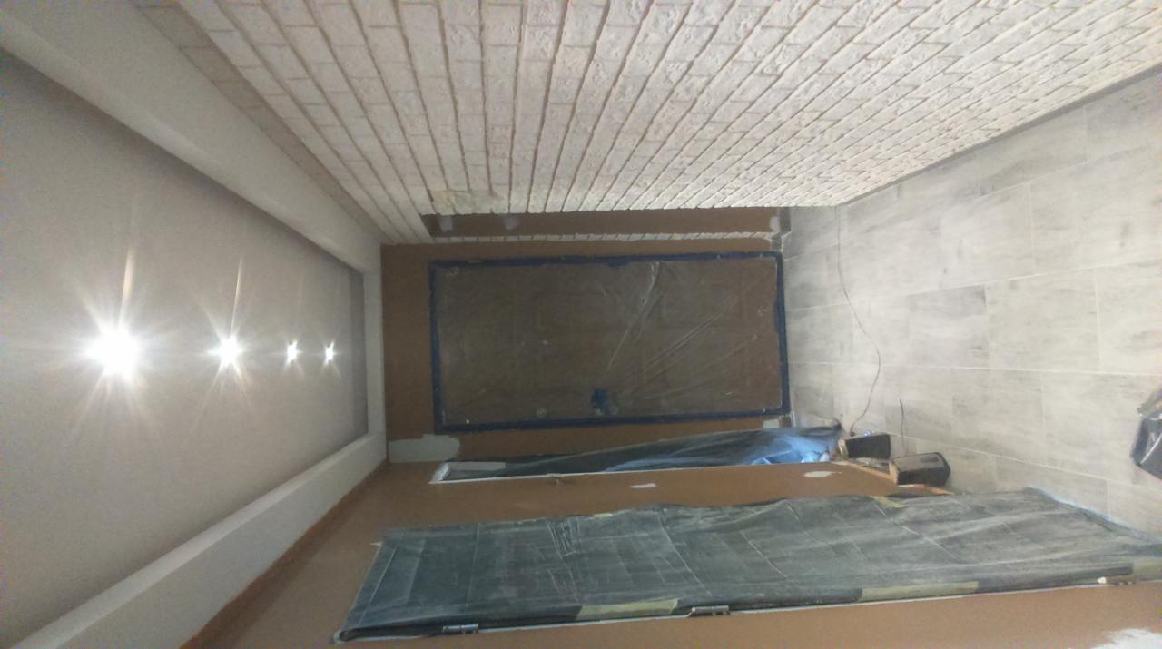 Wnętrze w trakcie prac wykończeniowych: sufit wykończony imitacją cegły, ściana z wbudowanymi punktami świetlnymi, zabezpieczona folią podłoga.