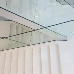 Nowoczesne schody z białego marmuru z szklaną balustradą z czarnymi krawędziami, widok z góry.