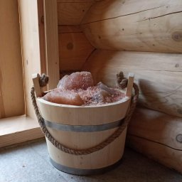 Duże drewniane wiadro wypełnione bryłami soli  jest elementem wyposażenia sauny.