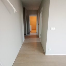Perfectly Home - Korytarz po remoncie w Starzyno z nową podłogą z paneli i świeżo pomalowanymi ścianami w odcieniach szarości, widoczne wystające kable.