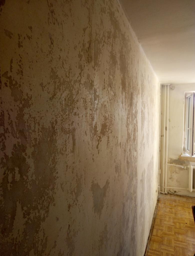 Ściana w pokoju przed remontem, z widocznymi śladami starej farby i nierównościami, przygotowana do dalszych prac wykończeniowych.