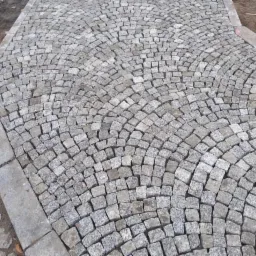 Ułożona kostka granitowa w kształcie wachlarza z obrzeżem, widok z góry.