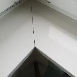 Jasny parapet z konglomeratu, widoczne łączenie pod kątem prostym i naklejka z adresem strony internetowej na ramie okiennej.