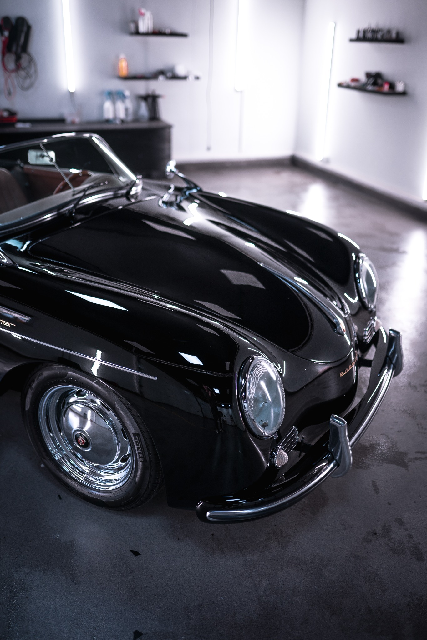 Błyszczący, czarny Porsche Speedster po renowacji, widok z przodu na detale karoserii i chromowane elementy, w tle warsztat z oświetleniem LED.