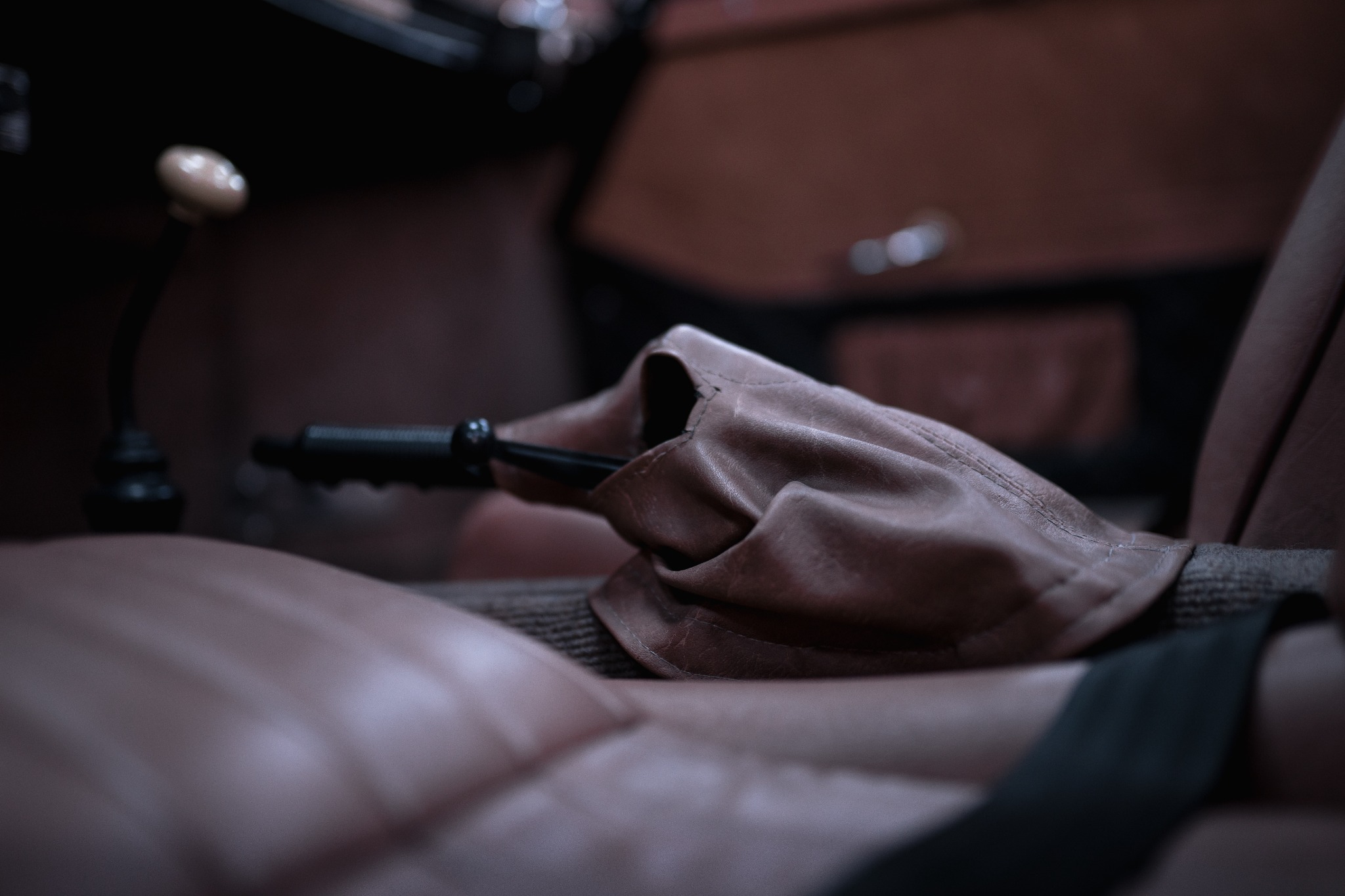 Wnętrze odrestaurowanego Porsche Speedster: brązowa skórzana tapicerka fotela, dźwignia zmiany biegów z jasną gałką i skórzanym mieszkiem, czarny pas bezpieczeństwa.