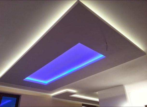 Podwieszany sufit z oświetleniem LED: prostokątna wnęka z niebieskim światłem, obramowana białym światłem LED w suficie podwieszanym.