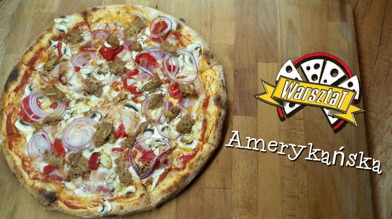 Pizza na cienkim cieście z pieczarkami, czerwoną cebulą, papryką i kawałkami mięsa, ułożona na drewnianym blacie, z widocznym logo pizzerii i napisem 'Amerykańska' dodanym cyfrowo.