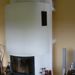 Nowoczesny, biały kominek z czarnym wkładem, wykończony brązowym blatem z granitu, otoczony dekoracjami, takimi jak świeczniki i szklanka.