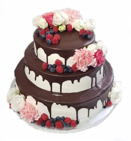 Trzypiętrowy tort weselny z polewą czekoladową, udekorowany świeżymi malinami, borówkami i kompozycjami z różowych i białych kwiatów na każdym poziomie.