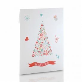 Biała kartka świąteczna z motywem choinki ułożonej z kwiatów i napisem 'Wesołych Świąt' na czerwonej wstążce.