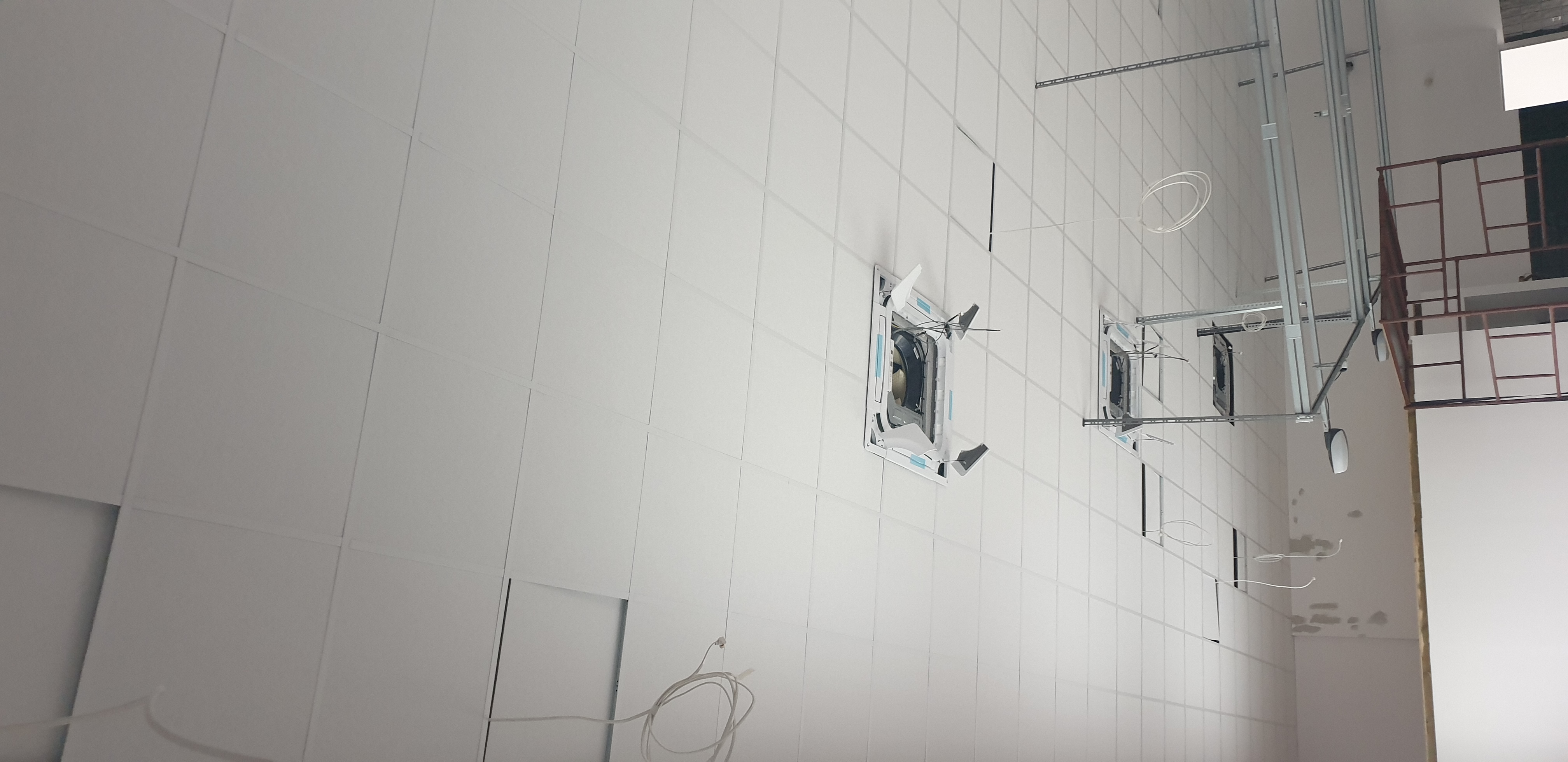 Montaż sufitu podwieszanego z płyt kartonowo-gipsowych z widocznymi elementami konstrukcyjnymi i instalacją oświetleniową w trakcie realizacji.