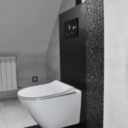 Nowoczesna, podwieszana toaleta w minimalistycznej łazience z czarno-białą mozaiką i matową czarną zabudową stelaża.